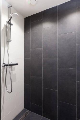 a bathroom with a shower with a black tile wall at Lovely 4P-apt near Canals - Utrecht City Centre in Utrecht