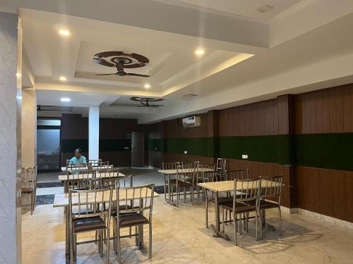 a dining room with tables and chairs and a person at Hotel Comfort Inn in Gurgaon