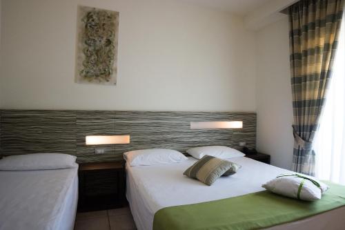 a hotel room with two beds and a window at Hotel Village Scoglio Della Galea in Capo Vaticano