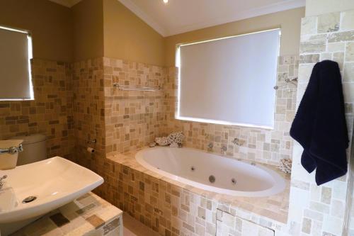 un baño con bañera y lavabo en Happy Tides Main House, en Struisbaai