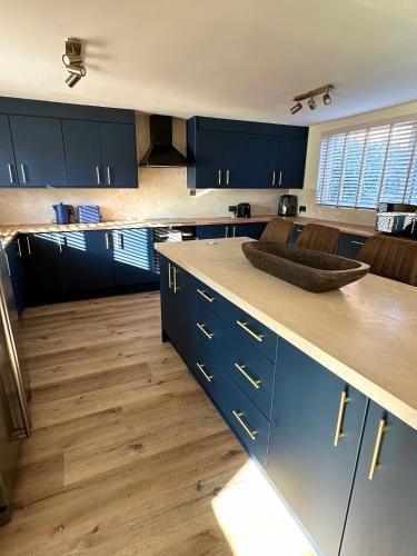 a kitchen with blue cabinets and wooden floors at Eden Escape - Bham Airport, NEC, HS2, JLR, Park Access in Sheldon