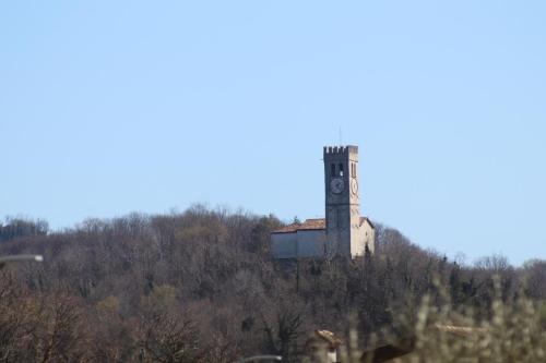 a clock tower on top of a hill with trees at Villa Gianfranca - sentiti come a casa in Corno di Rosazzo