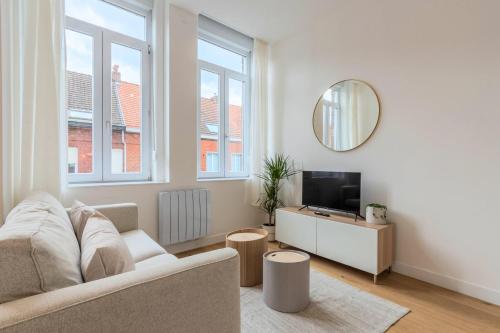 een witte woonkamer met een bank en een spiegel bij Appartement T2 proche tramway et commodités in Tourcoing