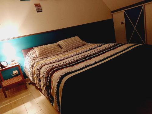 a bedroom with a bed with a blue wall at Location 24h du Mans in Parigné-lʼÉvêque