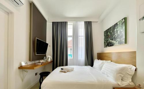 a bedroom with a large white bed and a window at ATAP Hotel in Kota Kinabalu