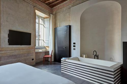 a bedroom with a bed and a tv and a tub at Palazzo Petrvs in Orvieto