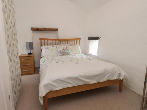 Un dormitorio con una cama con cabecero de madera. en The Outbuilding at Tyn Llan, en Cemaes