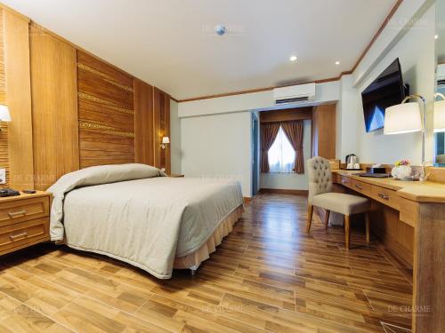 a bedroom with a bed and a desk and a sink at Decharme Hotel in Chiang Mai