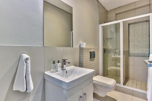 a white bathroom with a sink and a toilet at Heritage Square Apartments in Durbanville