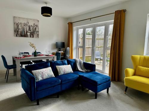 a living room with a blue couch and a yellow chair at Three-bedroom modern family home by the pond with free parking in Warfield