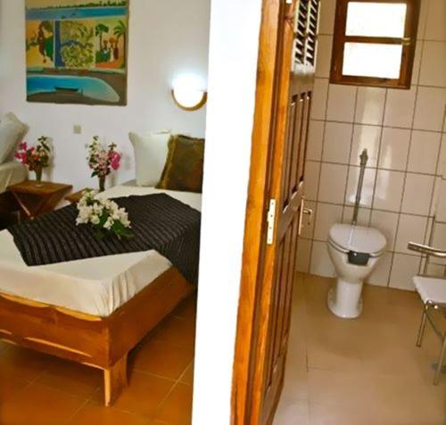 ein Schlafzimmer mit einem Bett und einem WC in einem Zimmer in der Unterkunft Casa Motel in Ziguinchor