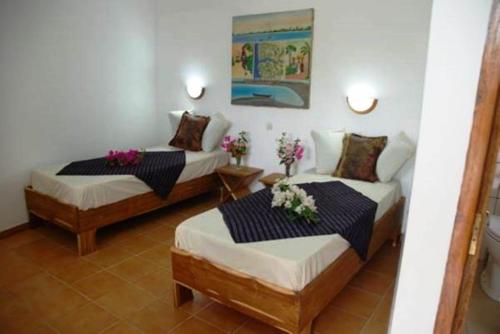 2 Betten in einem Hotelzimmer mit Blumen darauf in der Unterkunft Casa Motel in Ziguinchor
