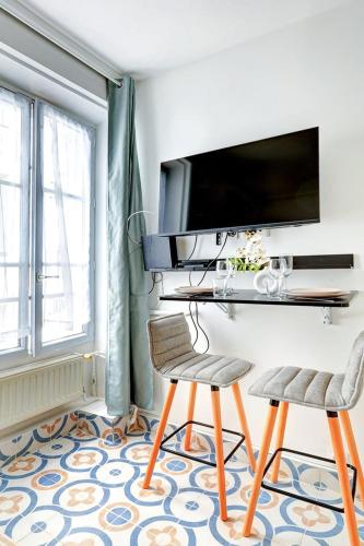 Cette chambre comprend deux chaises et un bureau avec une télévision. dans l'établissement 5012 Suite Lauriston - Cosy Studio at Trocadero, à Paris