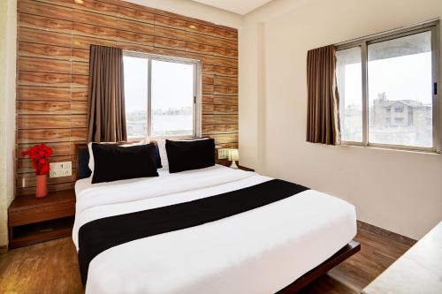 a bedroom with a large white bed and two windows at Super Collection O Airport Road Formerly Hotel Kyra in Ahmedabad