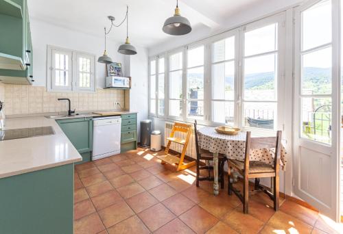 une cuisine avec une table, des chaises et des fenêtres dans l'établissement La Maison de Tartas, à Palau-de-Cerdagne