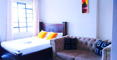 a couch and a chair in a room with a window at Essik Homes Studio 1 - Muthiga, Waiyaki Way in Nairobi