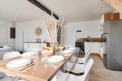 une cuisine et une salle à manger avec une table en bois et des chaises blanches dans l'établissement Maison pour 8, 500m du port et des plages, à Noirmoutier-en-l'lle
