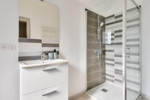 un bagno bianco con doccia e lavandino di Maison pour 8, 500m du port et des plages a Noirmoutier-en-l'lle