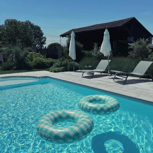 - une piscine avec 2 ombrelles et 2 chaises dans l'établissement Gîte - LA CLOCHETTE, à Lugon et l’Ile du Carney