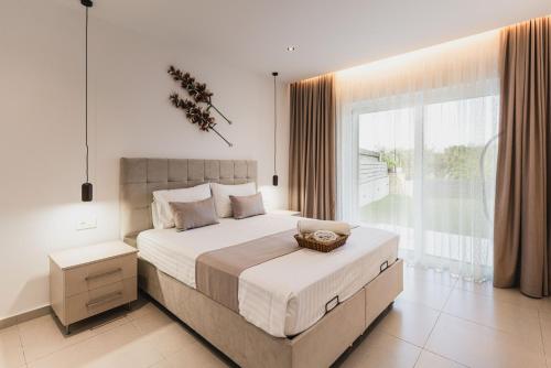 a bedroom with a large bed and a large window at G-Ammos 5 Star Villa by elite in Tragaki