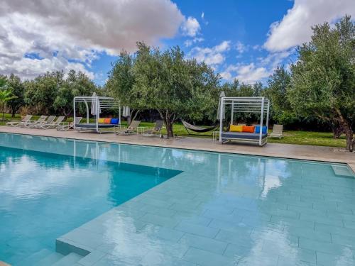 a swimming pool with chairs and a hammock at Villa Jardins D'Isa in Marrakech
