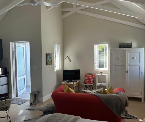 a living room with a red couch and a tv at Island Studio Apartment in Knysna