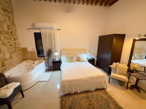 a bedroom with a tub and a bed and a bath room at Nov Antique - AKKO in ‘Akko