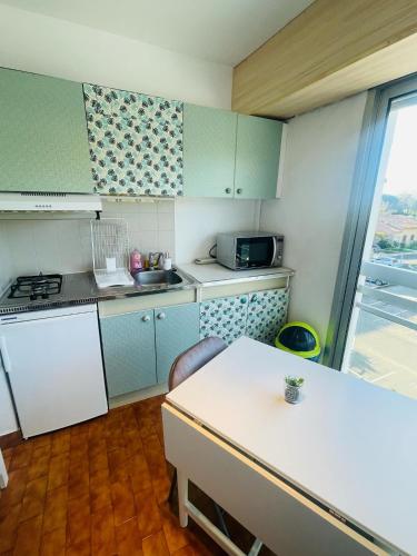 une cuisine avec des placards bleus et un comptoir blanc dans l'établissement Clim Wifi Pkg privé PONANT, à La Grande Motte