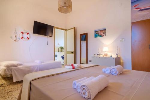 a bedroom with two beds and a tv on the wall at Alla Rosa Dei Venti - Sud Wind House in Torre Specchia Ruggeri