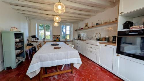 a large kitchen with a table and a tv at Détente au cœur du Perche in Senonches