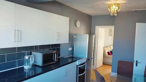 eine Küche mit einer Theke, einer Mikrowelle und einem Kühlschrank in der Unterkunft rhyl apartments in Rhyl