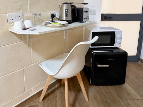 a white chair sitting next to a counter with a microwave at Mini Studios in Central Victoria in Victoria