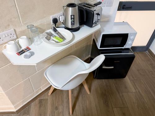 a white chair sitting next to a counter with a coffee maker at Mini Studios in Central Victoria in Victoria
