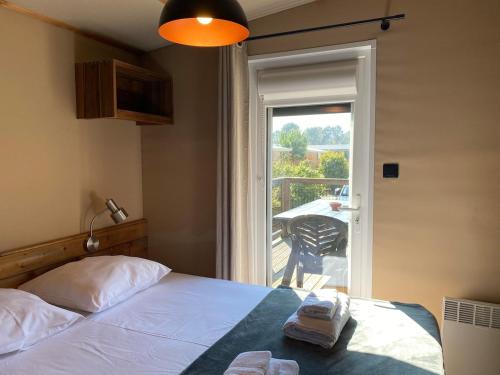 - une chambre avec un lit et une porte donnant sur un balcon dans l'établissement Chalet du Bassin Arcachon - Camping Parc aquatique, à Gujan-Mestras