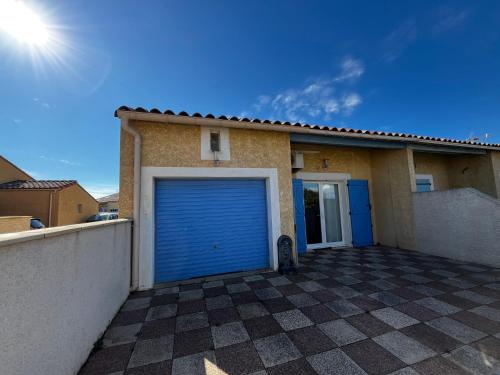 拉努韦勒港Maison de vacances à la mer的车库,房子里有一个蓝色的车库门