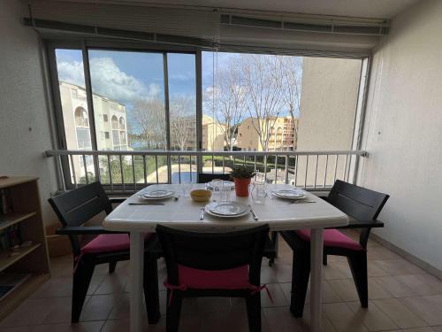 une table de salle à manger avec des chaises et une grande fenêtre dans l'établissement Appt 2 pièces 4 couchages CAP D 'AGDE CT590-233, au Cap d'Agde