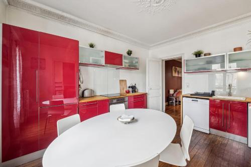 une cuisine avec une table blanche et des placards rouges dans l'établissement Le Marceau - Wifi Courbevoie, à Courbevoie