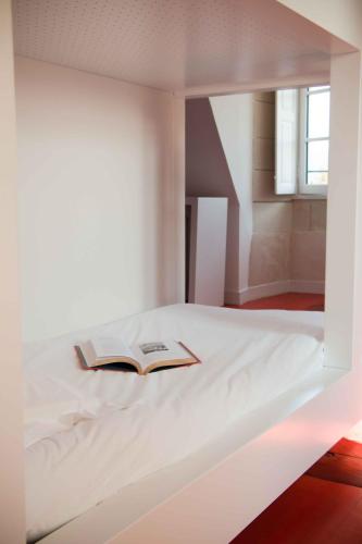 a bed with a book on top of it at Surprenantes - Château du Pé in Saint-Jean-de-Boiseau