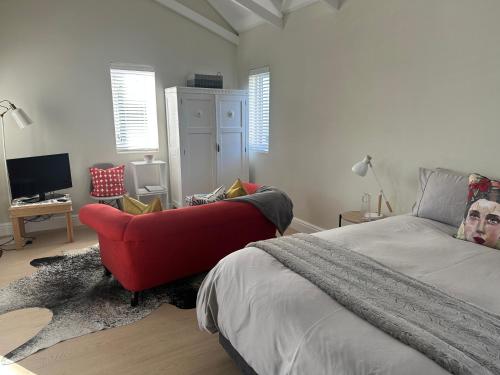 a bedroom with a bed and a red couch at Island Studio Apartment in Knysna