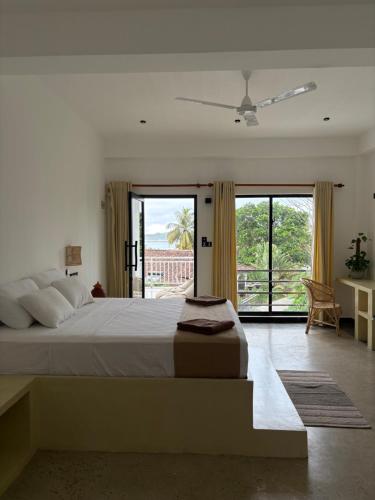 a bedroom with a large bed and a large window at Calma - Surf, Yoga & Coffee on a Private Beach in Dickwella