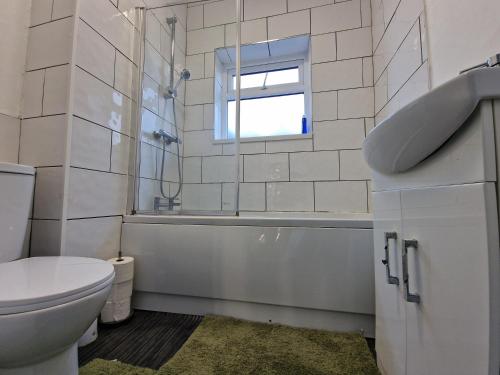 a bathroom with a toilet and a sink and a window at Nice Living Serviced Accommodations 12 in Coventry