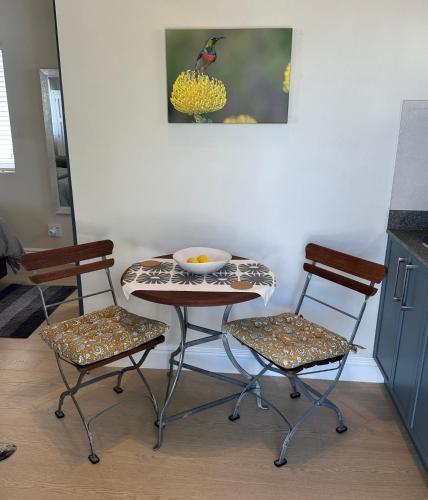 a table and two chairs in a kitchen with a bowl on it at Island Studio Apartment in Knysna