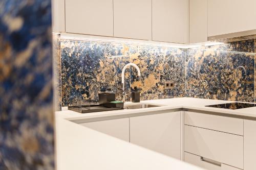 a white kitchen with a sink and a mosaic wall at Safira Suites 101 in Funchal