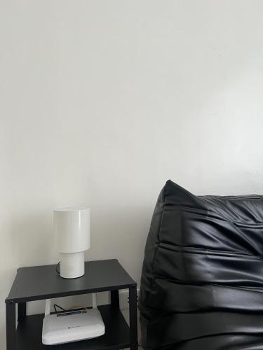 a lamp on a table next to a black couch at The Bauhouse Studio with Balcony near Eastwood in Manila