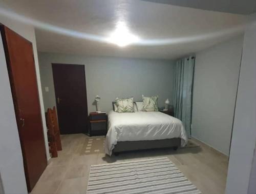 a bedroom with a white bed and a room with a door at Goggas Nest BNB & Restaurant in Matsapha