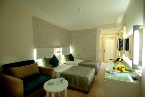 a room with a bed and a couch and a table at Grand Okan Hotel in Alanya