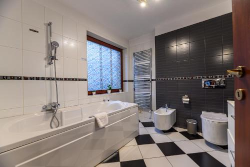 a bathroom with a tub and a toilet at Holiday Belview - Le grand Brașov in Braşov