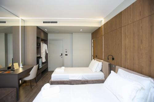 a hotel room with two beds and a desk at Charm Hotel in Vlorë