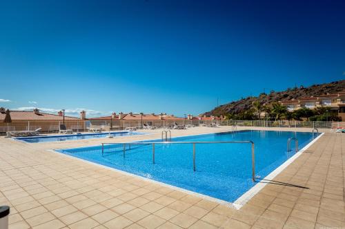 a large swimming pool with blue water at Townhouse Playa Negra in Puerto de Santiago