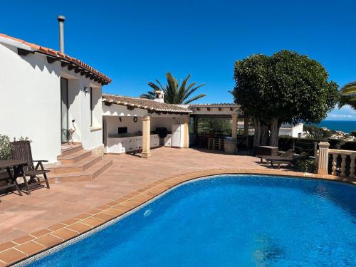 a villa with a swimming pool in front of a house at Villa Balcon al Mar in Jávea